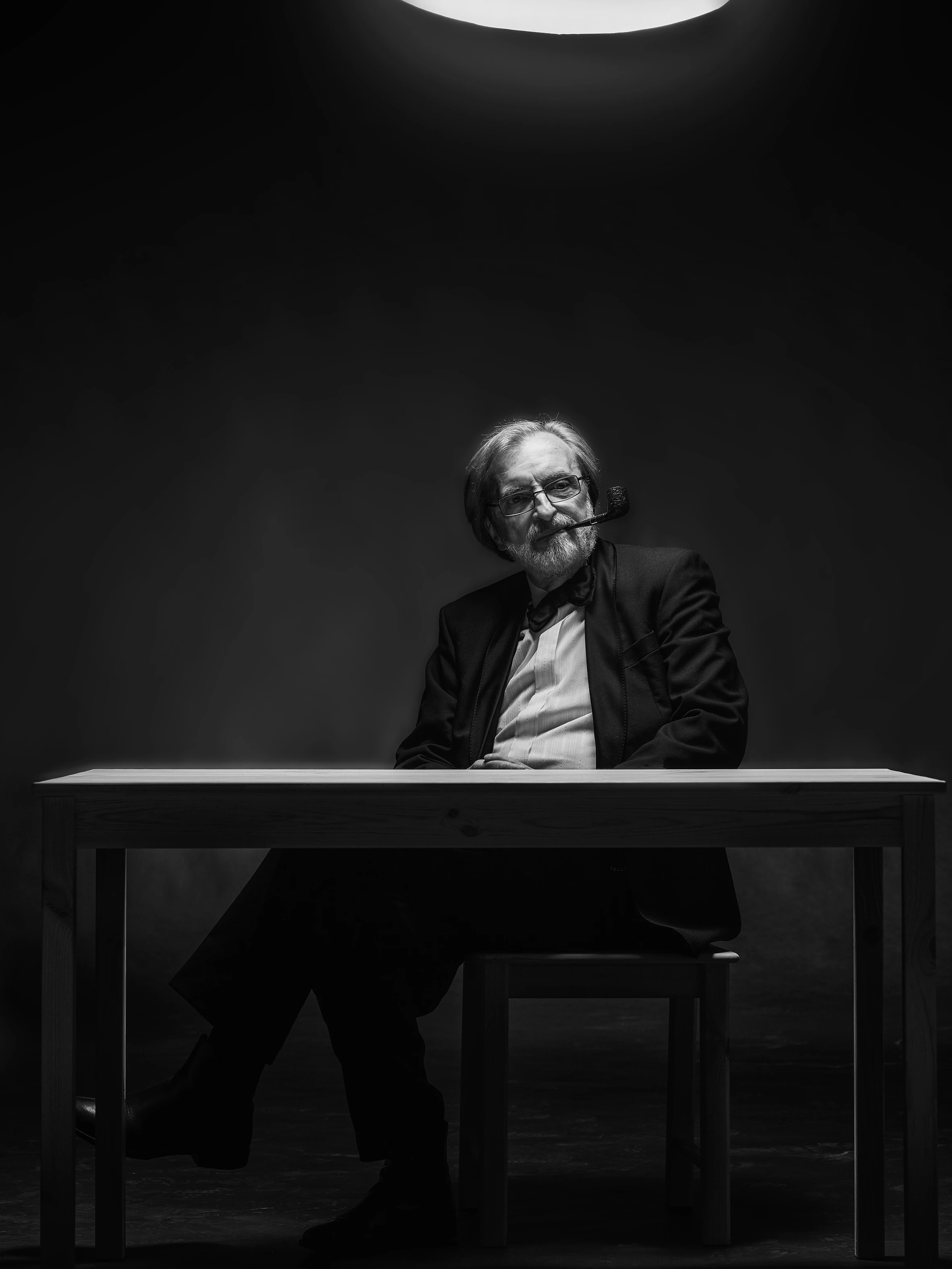 elderly man sitting behind a desk monochrome