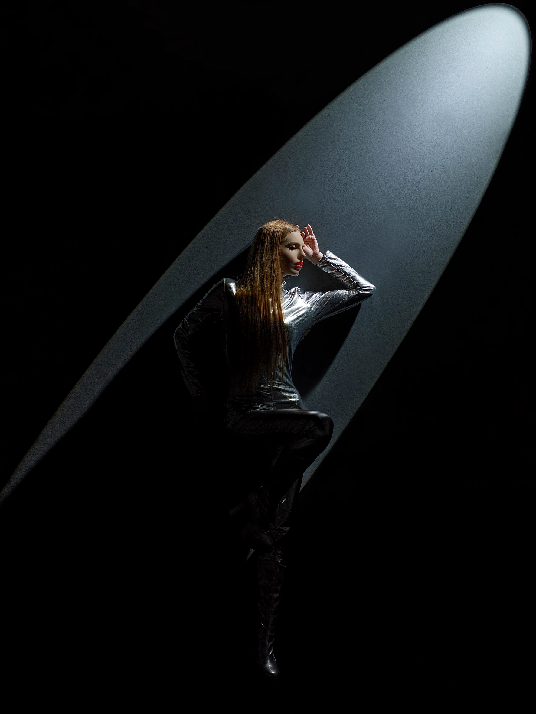 girl in a full silver suit standing under spotlight